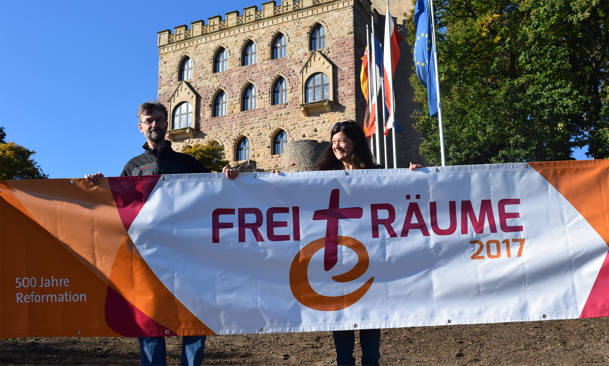 Ob Hambacher Schloss oder Martin-Butzer-Haus – das Logo FreiTräume sieht überall glänzend aus und gibt dem Geist der Orte einen Namen. Landesjugendpfarrer Geith und Öffentlichkeitsreferentin Deutschel stellten das Banner vor.